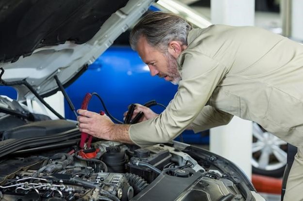 A car’s battery is being repaired at an auto repair shop.